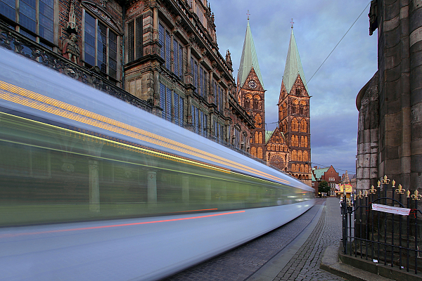 Straßenbahn fährt zur blauen Stunde am Rathaus vorbei. Im Hintergrund sieht man den Dom.
