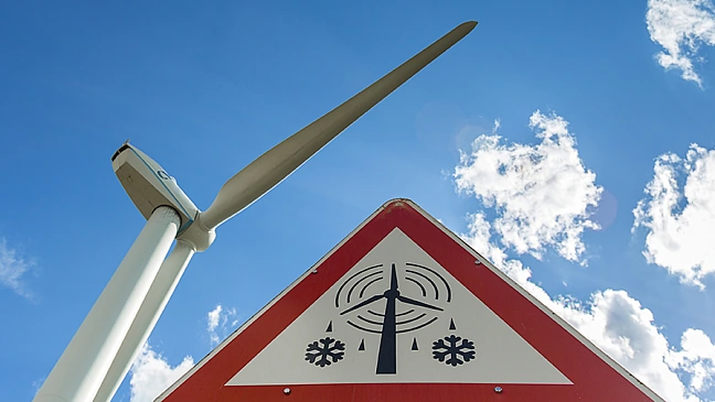 Windrad mit blauem Himmel und Wolken, Warnzeichen für Eisfall