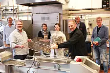 Fish is poured onto a grid to dry. The project participants stand around it.